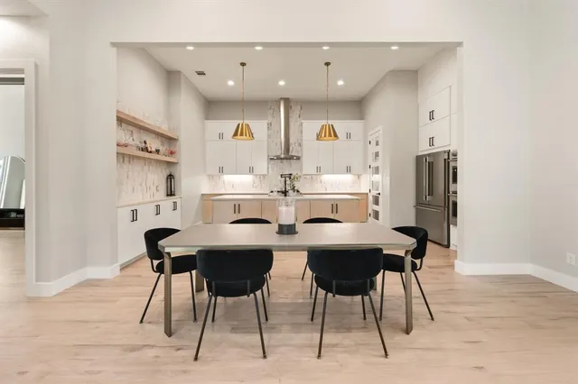 a dining room with stainless steel appliances kitchen island granite countertop a dining table chairs and a refrigerator