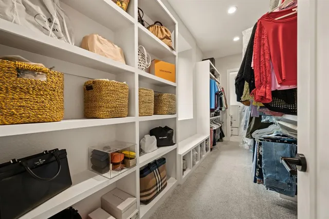 a view of walk in closet with clothes and shoes