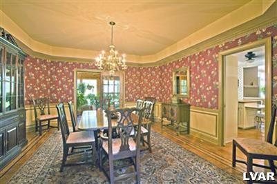 Formal dining room with French doors to sun room, chair rail and shadow boxing, recessed ceiling, and dentil molding.