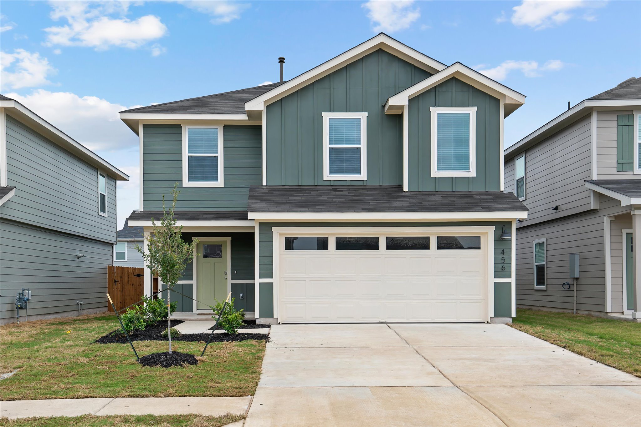 A striking two-story residence with a tidy lawn and ample driveway, featuring a double garage and charming entryway.
