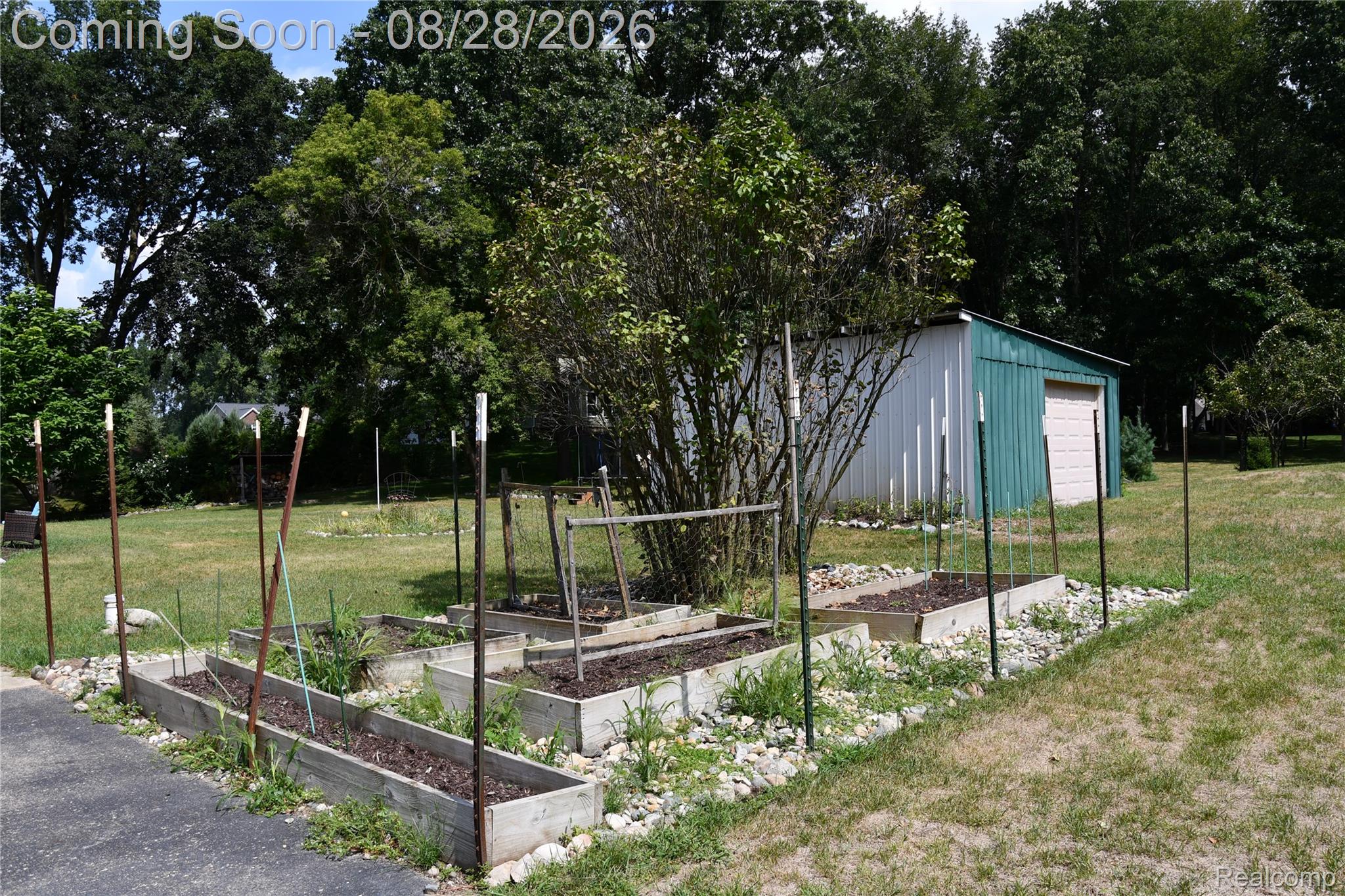 9039 Peer Road South Lyon, MI 48178 - Photo 17 of 47 Raised garden beds with rock landscaping, a metal storage shed, and mature trees