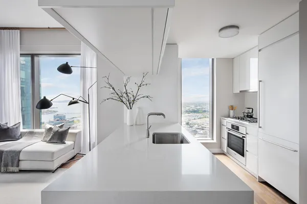 a large white kitchen with a large window and stainless steel appliances