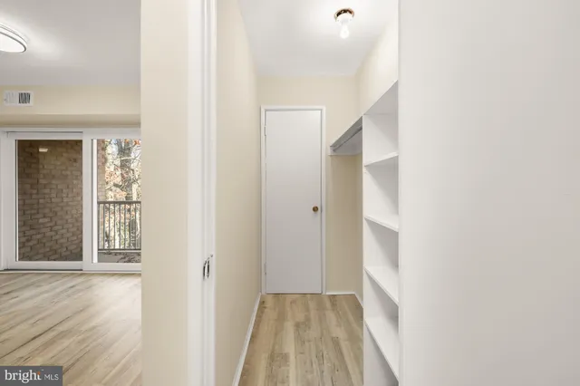 a view of a hallway with wooden floor and a bathroom
