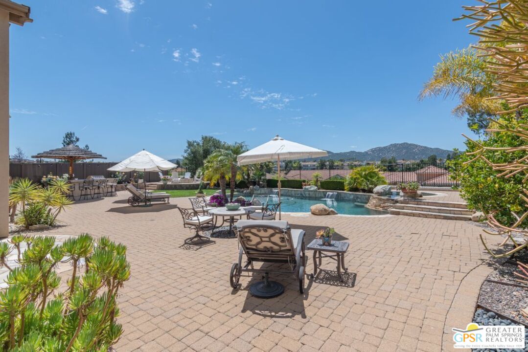 45211 Willowick Street Temecula, CA 92592 - Photo 55 of 69 a view of a patio with dining table and chairs under an umbrella with a fire pit