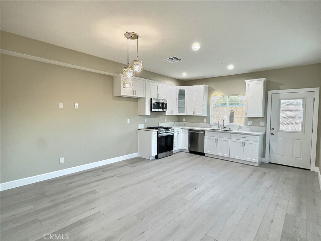 15909 Merrill Avenue, Unit 1 Fontana, CA 92335 - Photo 3 of 7 a view of kitchen with granite countertop stainless steel appliances cabinets a sink and a wooden floor