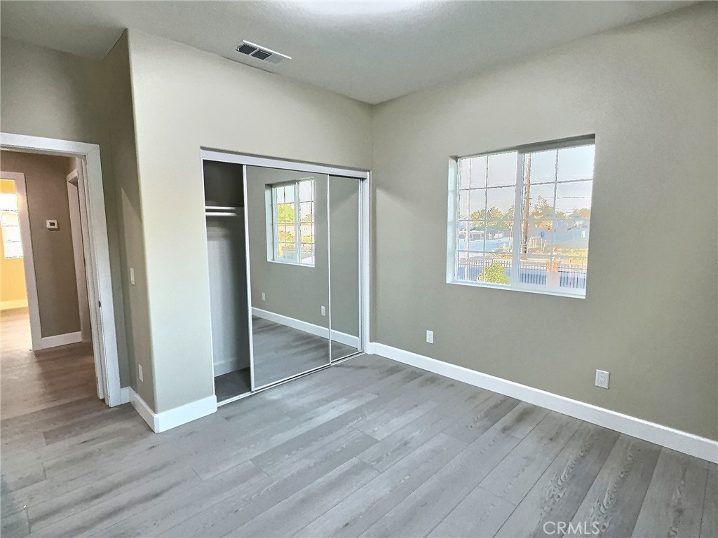 15909 Merrill Avenue, Unit 1 Fontana, CA 92335 - Photo 5 of 7 an empty room with wooden floor and windows