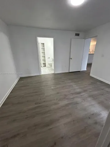 a view of an empty room with wooden floor and windows