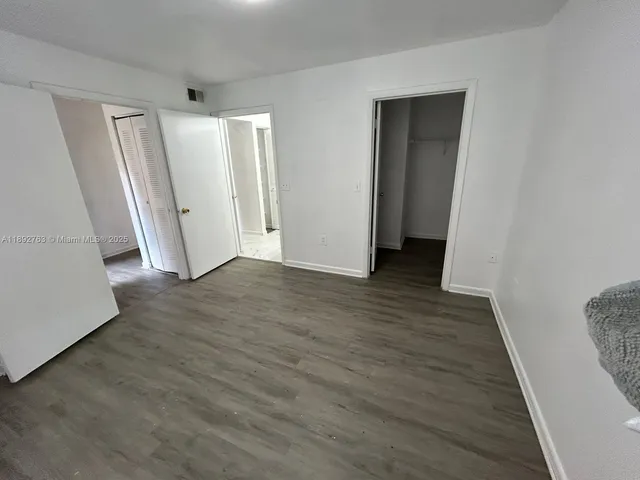 an empty room with wooden floor and entrance