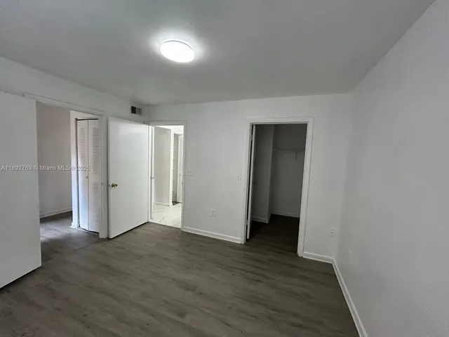 a view of an empty room with wooden floor and closet