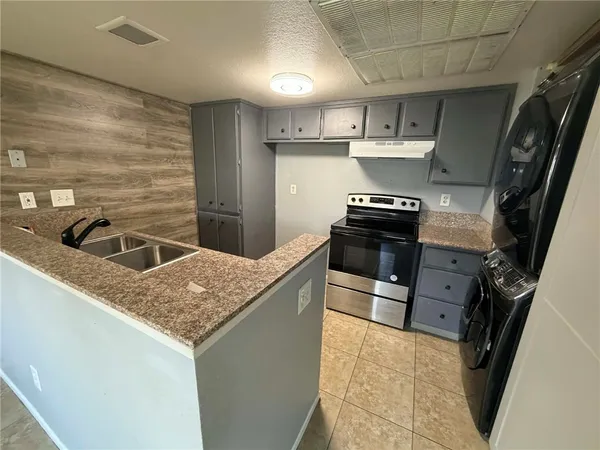 a kitchen with granite countertop a stove and a sink