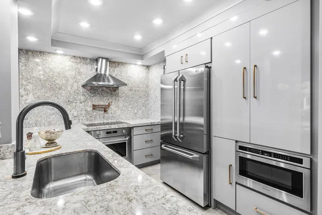 a kitchen with stainless steel appliances kitchen island granite countertop a refrigerator a sink and a stove