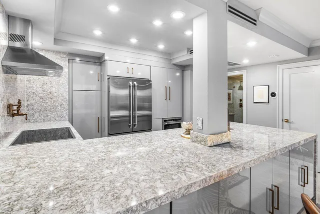 a kitchen with stainless steel appliances kitchen island granite countertop a refrigerator and a sink