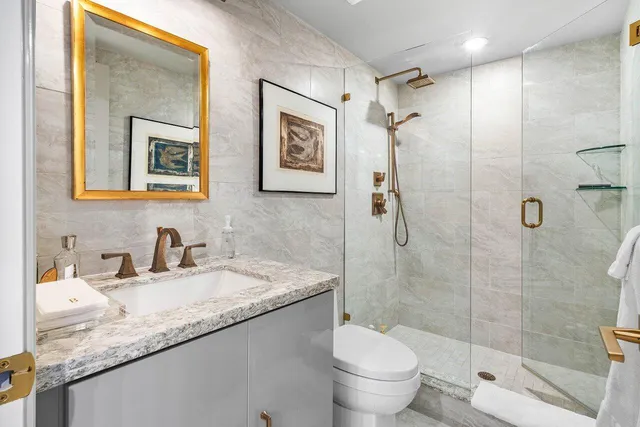 a bathroom with a granite countertop sink a toilet and shower