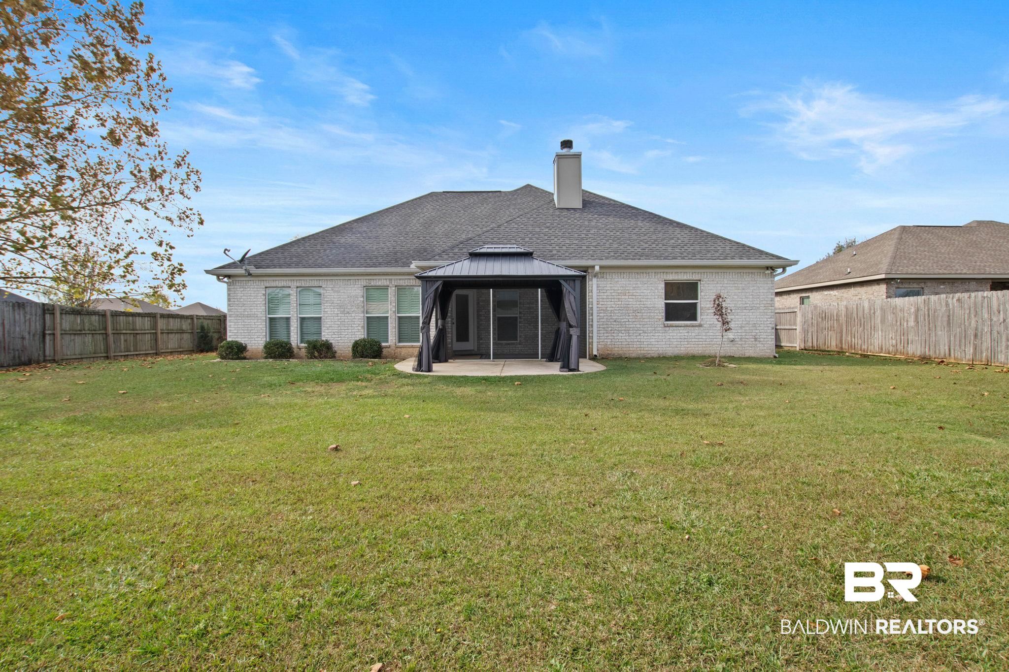 17376 Bankhead Boulevard Fairhope, AL 36532 - Photo 56 of 73 Rear view of property featuring a fenced backyard, brick siding, a chimney, and a gazebo
