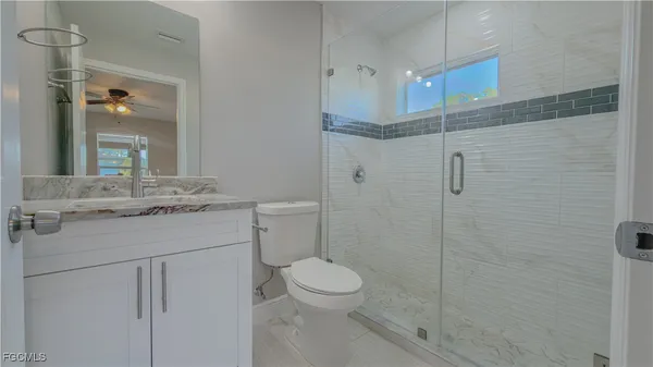 a bathroom with a granite countertop sink toilet a mirror and shower