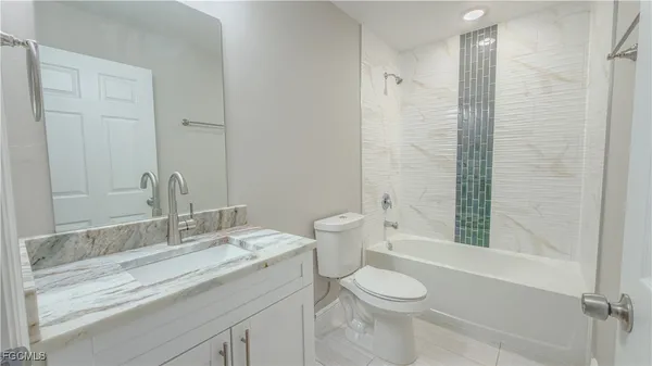 a bathroom with a granite countertop sink a toilet and shower