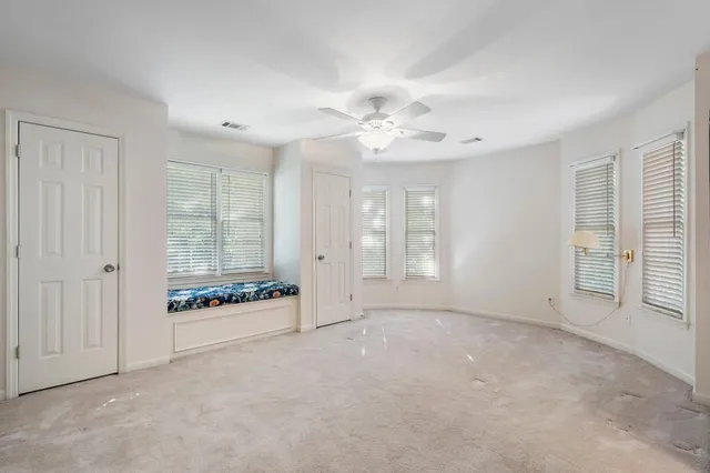 an empty room with windows and ceiling fan