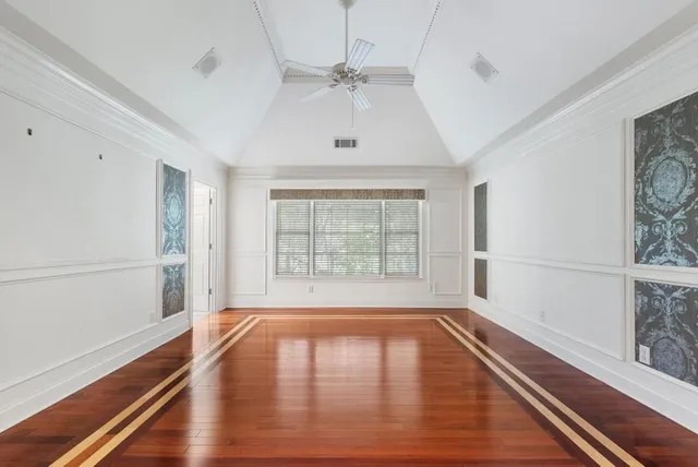 a view of an empty room with a window and wooden floor