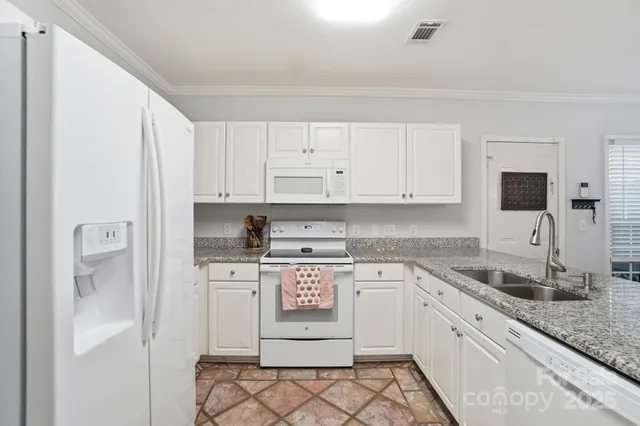 a kitchen with granite countertop white cabinets and white appliances