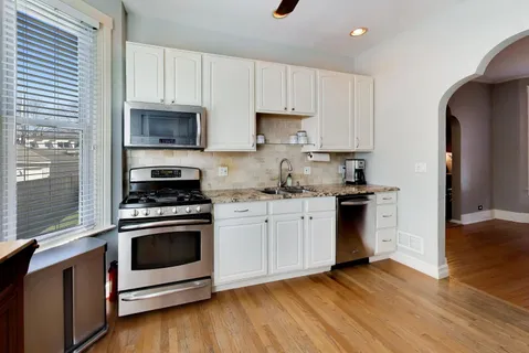 a kitchen with cabinets stainless steel appliances and wooden floor