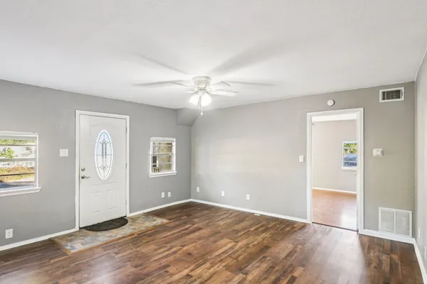 an empty room with wooden floor and windows