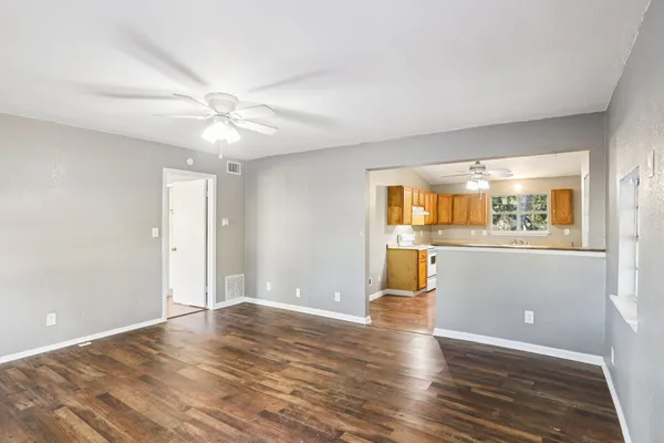 a view of an empty room with window and wooden floor