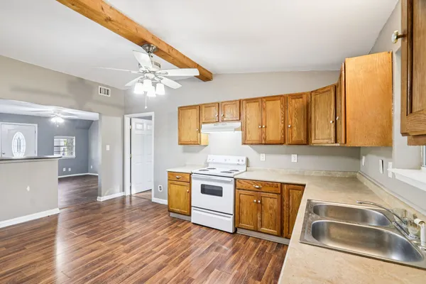 a kitchen with stainless steel appliances granite countertop a sink a stove cabinets counter space and wooden floor