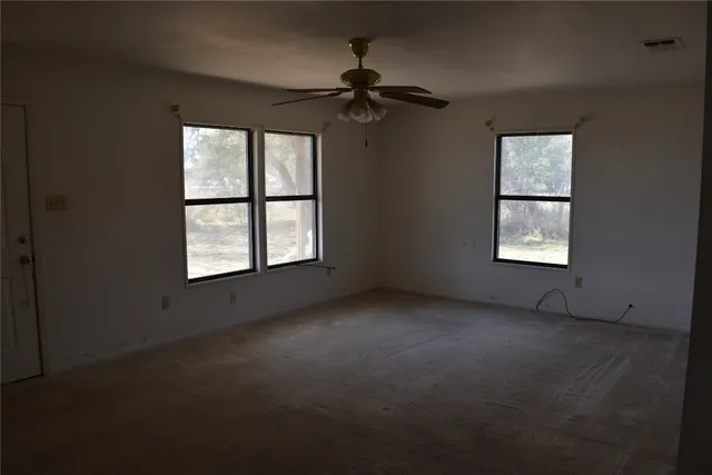 an empty room with windows and fan