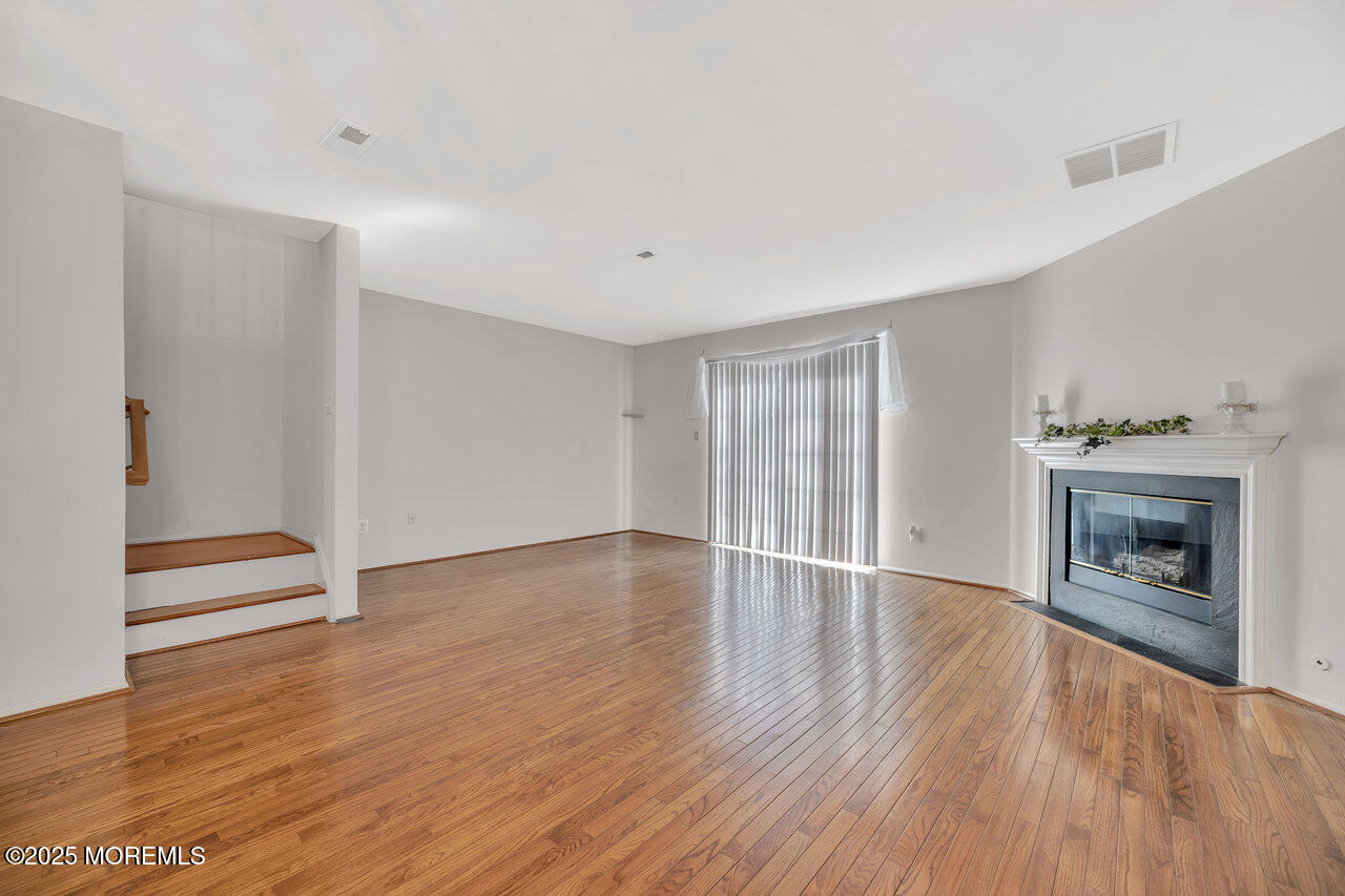 Undisclosed Address Holmdel, NJ 07733 - Photo 13 of 28 a view of an empty room with wooden floor fireplace and a window
