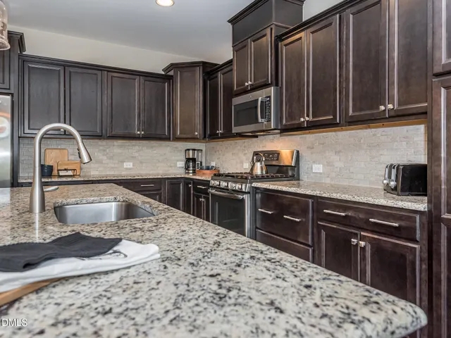 a kitchen with kitchen island granite countertop wooden cabinets and stainless steel appliances