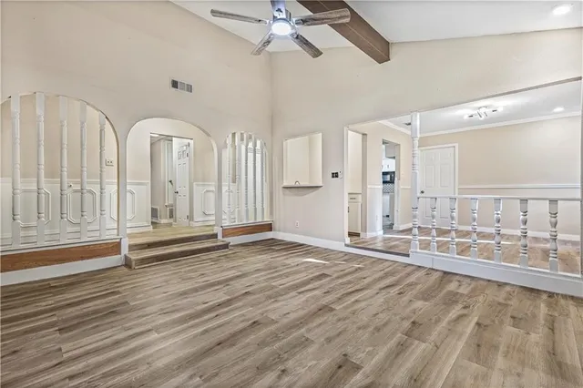 an empty room with wooden floor and ceiling fan