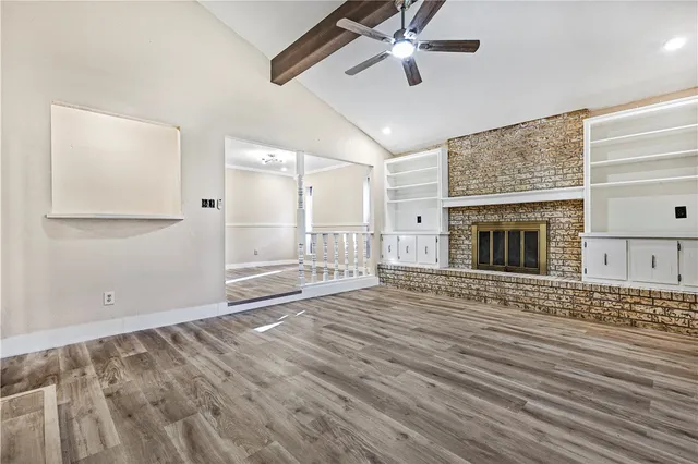 an empty room with wooden floor a ceiling fan and windows