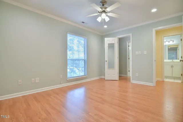 an empty room with wooden floor closet and windows