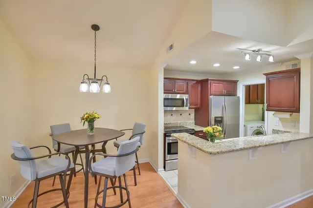 a kitchen with stainless steel appliances kitchen island granite countertop a table and chairs