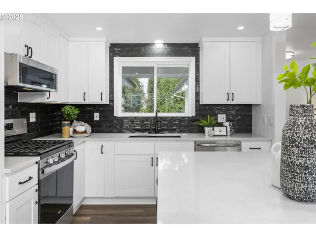a kitchen with stainless steel appliances granite countertop a stove a sink and a microwave