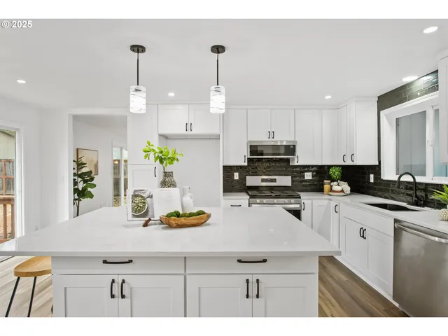 a kitchen with kitchen island granite countertop a sink a counter space appliances and cabinets