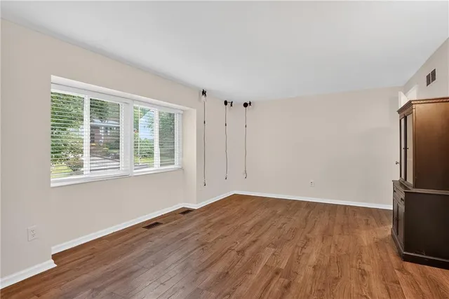 a view of empty room with wooden floor and window