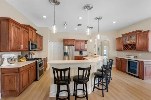 a kitchen with stainless steel appliances kitchen island granite countertop a stove a sink a microwave a center island and chairs