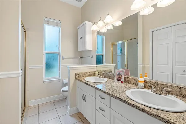 a bathroom with a granite countertop double vanity sink a mirror and a shower
