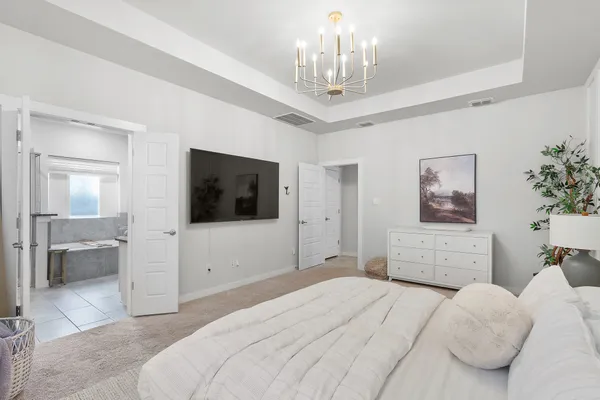a bedroom with a large bed and a chandelier