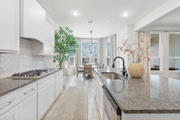 a kitchen with granite countertop a stove and white cabinets