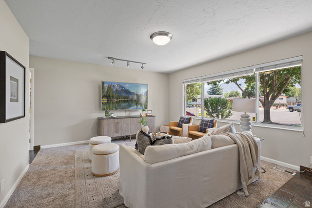 2370 Quail Run Circle East Sandy, UT 84093 - Photo 4 of 54 Bright living area featuring large windows, neutral paint, track lighting, and soft carpet flooring