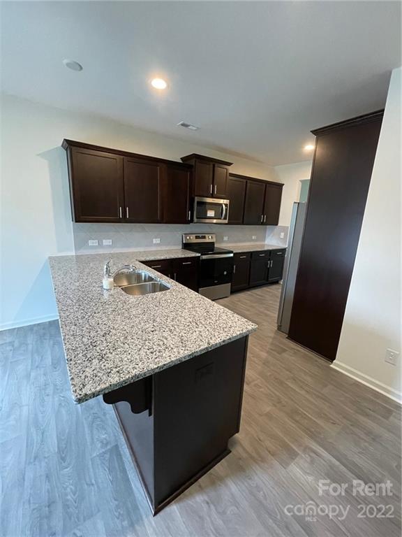 809 Alexander Commons Drive, Unit 34 Monroe, NC 28112 - Photo 9 of 28 a kitchen with stainless steel appliances kitchen island granite countertop wooden floor sink and stove