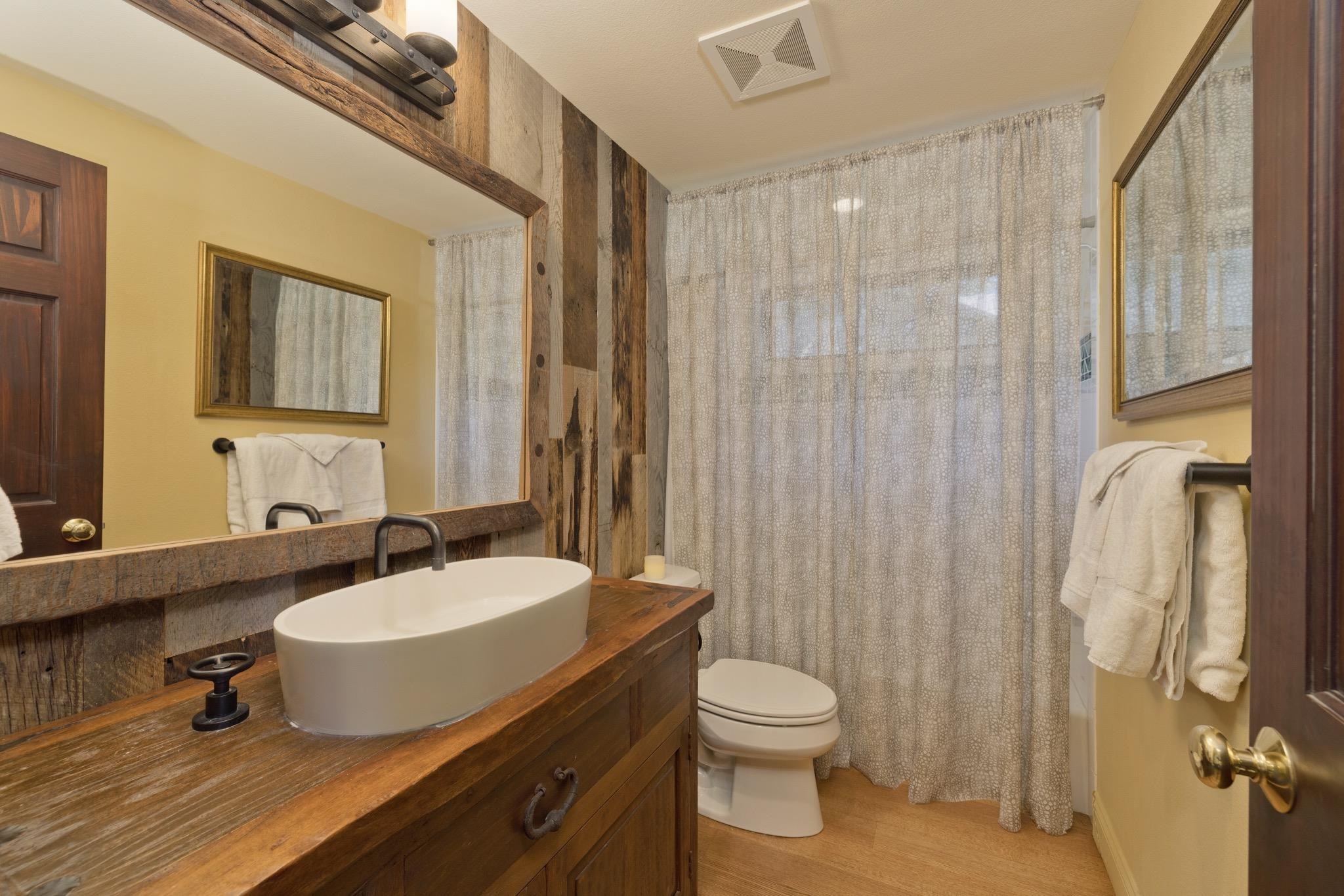 378 Ridge Way Mammoth Lakes, CA 93546 - Photo 34 of 43 Bathroom featuring a wood-finish vanity with a vessel sink, dark wood accent wall, and wood-finish flooring