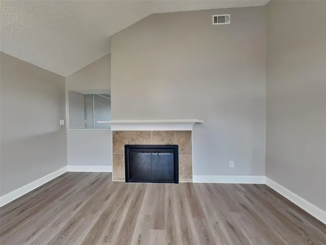 an empty room with a fireplace and wooden floor