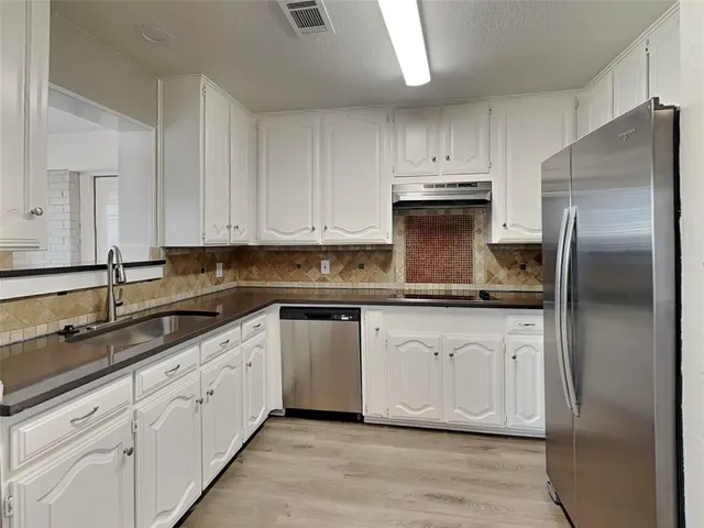 a kitchen with stainless steel appliances granite countertop a refrigerator and a sink