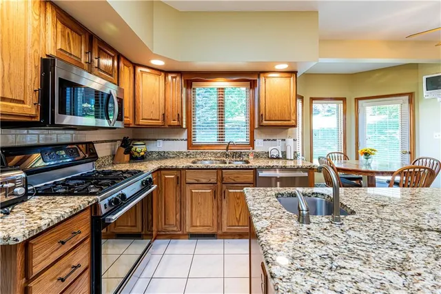 a kitchen with stainless steel appliances granite countertop a stove a sink and a microwave