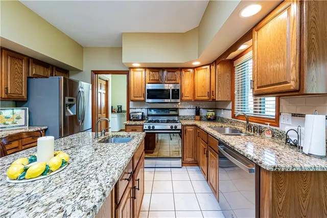 a kitchen with stainless steel appliances granite countertop a stove refrigerator and a sink