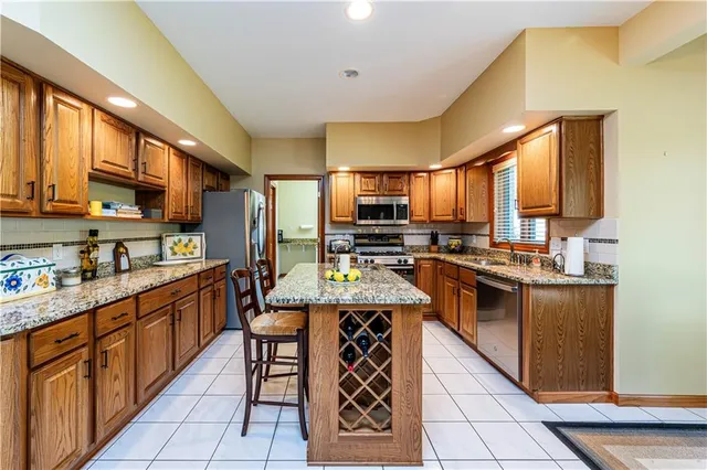 a kitchen with stainless steel appliances kitchen island granite countertop a stove a sink dishwasher and a refrigerator