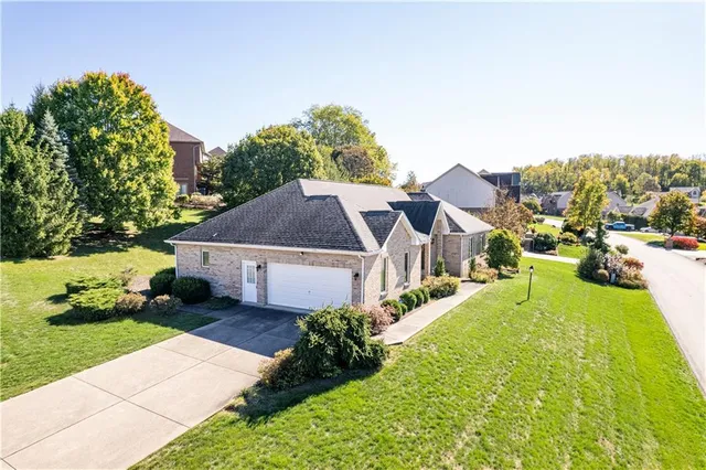 a view of a white house with a big yard plants and large trees